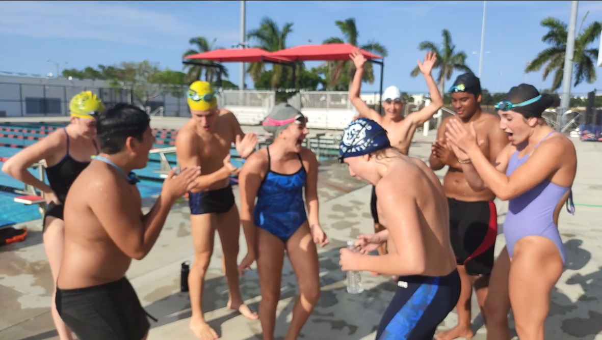 Four Strokes swimmers celebrating together beside an outdoor pool